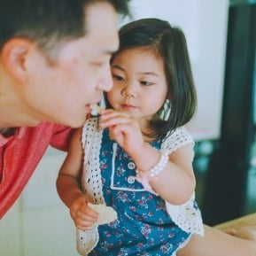 little girl feeding dad with cream cracker